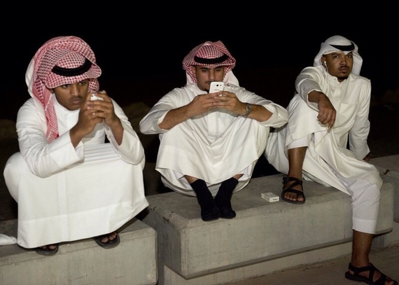 Kuwaiti men look at their cell phones as they listen to opposition lawmakers during a protest in Kuwait City